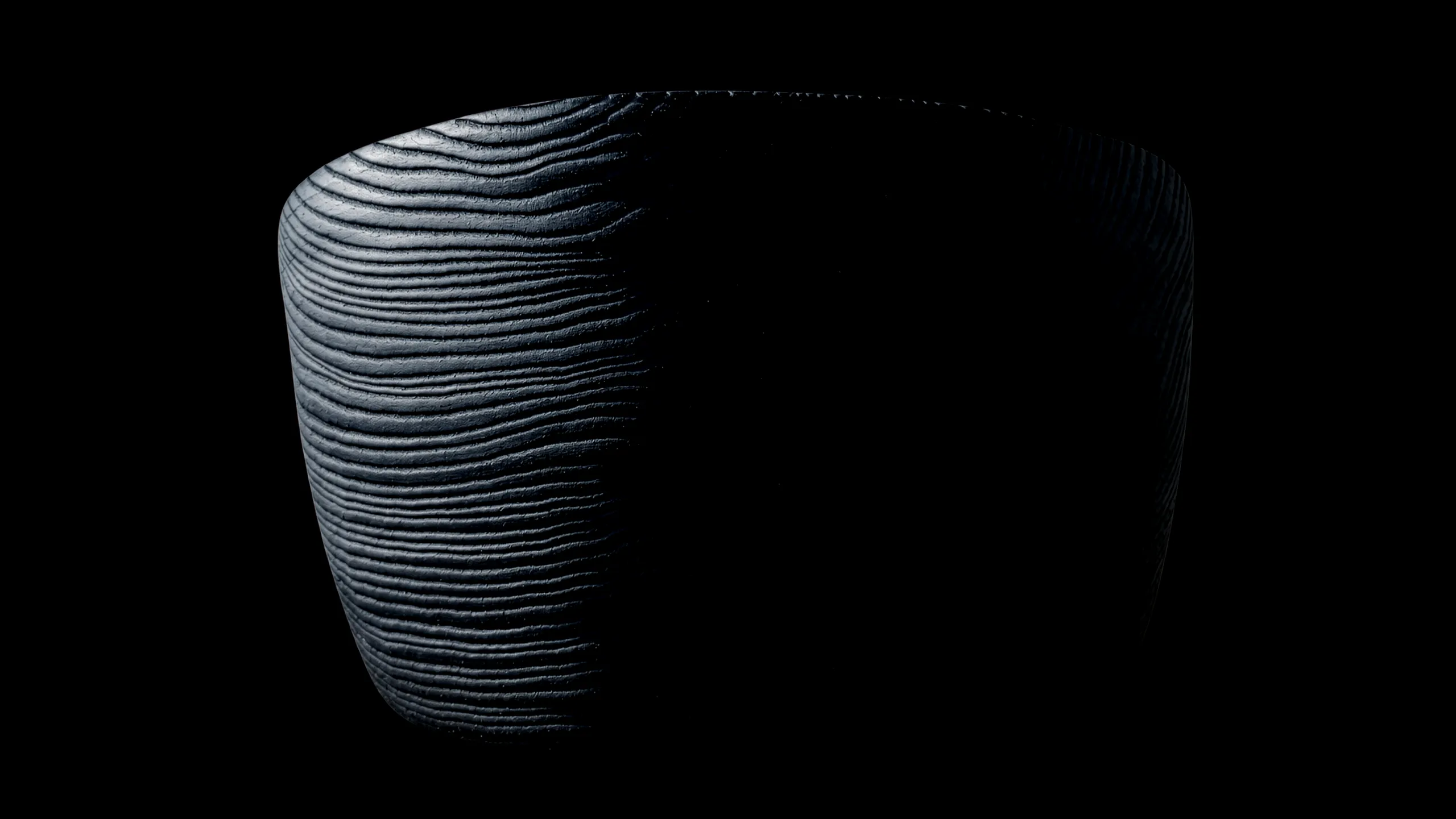 Dark ash bowl with a ridged wood grain against a black background, lit from the left